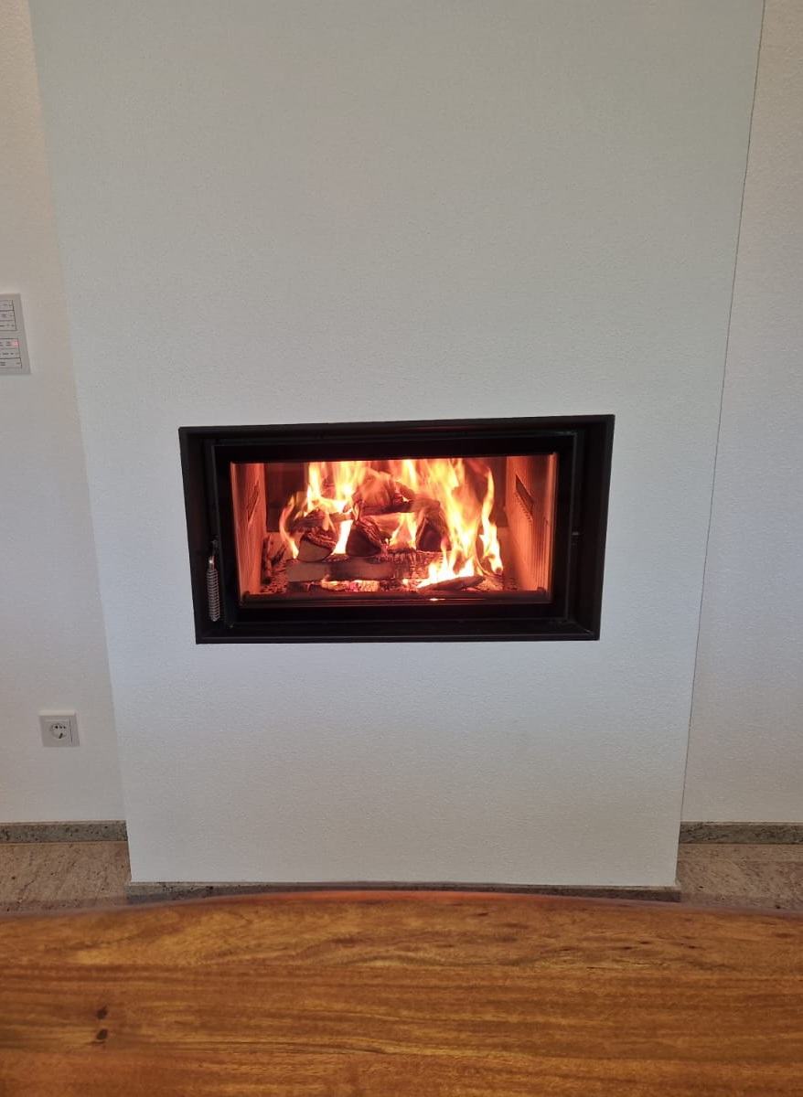 Loderndes Feuer in einem modernen Kamineinsatz in weißer Wand